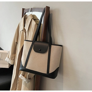 Détail du sac cabas en toile avec garniture en cuir noir sur un cintre en bois
