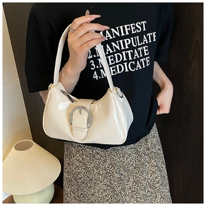 Detailed view of cream-colored patent leather underarm bag with silver round buckle strap
