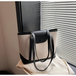 Détail du sac cabas en toile avec coutures en cuir noir et fermeture à bouton-pression