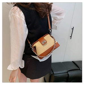 Detail showing contrast straw and brown leather crossbody bag with silver lock and chain