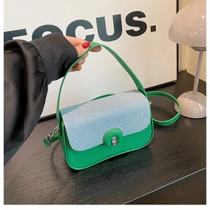 Détail du sac boîte vert avec rabat à rayures et fermoir rotatif sphérique en métal argenté