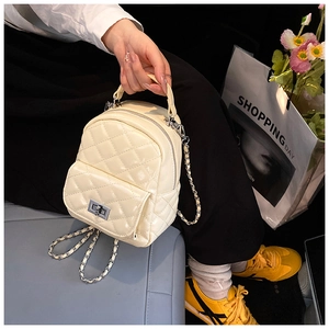 Detail of creamy white quilted mini backpack with metallic twist lock and chain strap