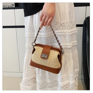 Detail of a contrasting straw and brown leather crossbody bag with silver twist lock