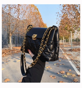 Detail der schwarzen Stepptasche mit goldener Schnalle vor warmem Herbsthintergrund