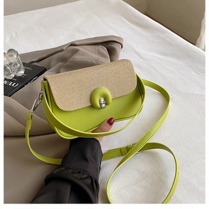 Détail du sac bandoulière en cuir vert fluo avec texture paille beige et fermoir argenté