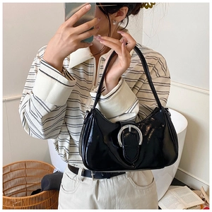 Detail of black patent leather underarm bag with iconic silver buckle and shoulder strap