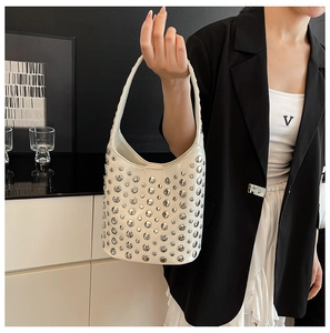 Detail of creamy white leather handbag with silver rivets and integrated shoulder strap