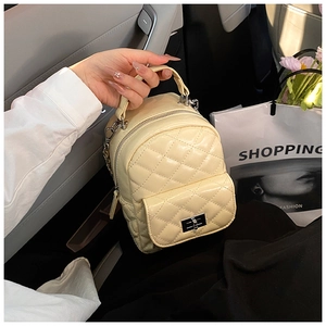 Close-up of quilted cream backpack featuring silver metal twist lock and chain strap detail