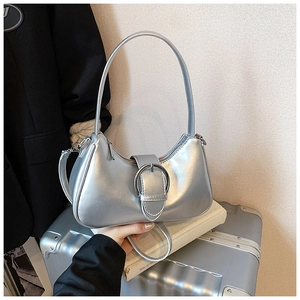 Close-up of the silver crescent underarm bag with metallic texture and circular buckle