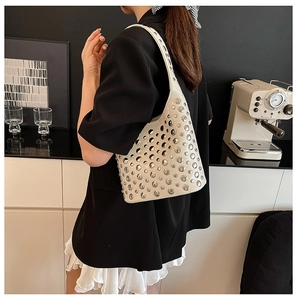 Close-up of a white half-moon underarm bag featuring silver rivets and modern studded style