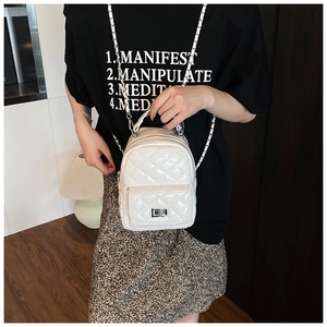 Close-up of white quilted mini backpack with silver twist lock and chain strap