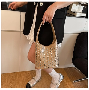 Detail of beige bucket bag featuring silver rivets and elegant embroidery stitching