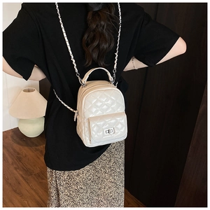 Fashionable cream white quilted backpack with chain straps shown on a model