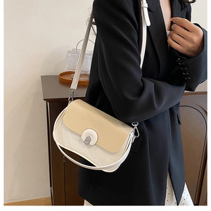Détail d'un sac bandoulière beige avec rabat texturé et boucle métallique sur un modèle