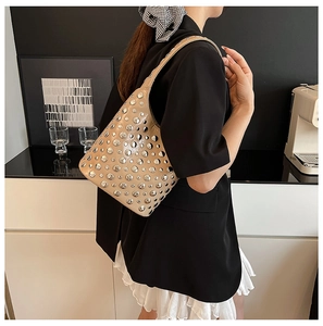 Detailed view of beige studded crescent shoulder bag worn with a black blazer outfit