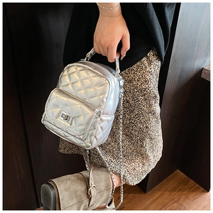 Detail of silver quilted mini backpack with glossy metallic finish and chain strap