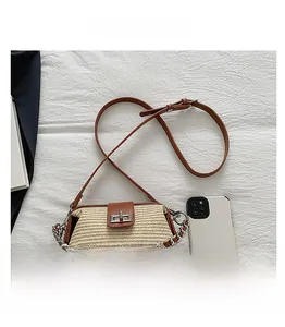 Straw and leather crossbody bag detail with metal chain and phone size reference
