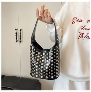 Detail of black leather bucket bag featuring polished silver rivet studs and a handle