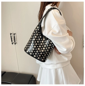 Detail of black bucket bag featuring silver rivet studs and adjustable leather strap
