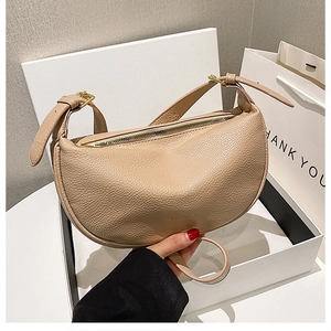 Detail of beige crescent shoulder bag with pebbled leather texture in gift box