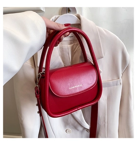 Close-up of vibrant red leather handbag with gold metal buckles and adjustable strap