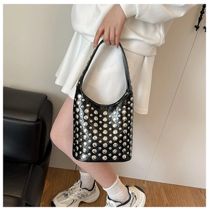 Detail of glossy black leather shoulder bag featuring dense silver metal rivets and studs