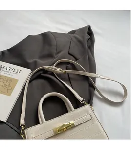 Detail of crocodile embossed cream bag with golden rotary lock on premium blazer