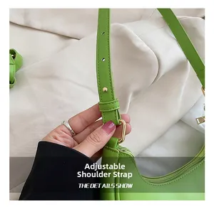 Detail showing the adjustable leather strap and golden circular hardware of the green moon bag