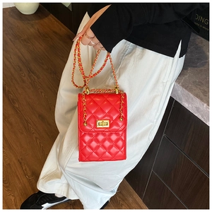 Detail of red quilted leather cross body bag with golden chain strap and twist lock