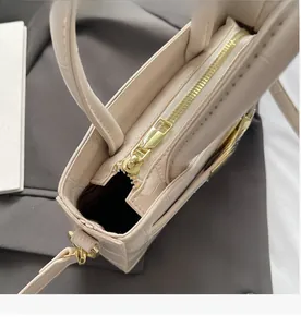 Close-up of golden zipper and crocodile pattern texture on beige minimalist handbag