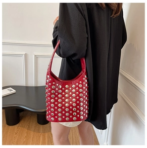 Detail of red glossy patent leather bucket bag featuring silver rivet studs and top handle