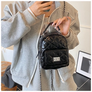 Detailed view of mini black quilted backpack with silver clasp and metal chain straps