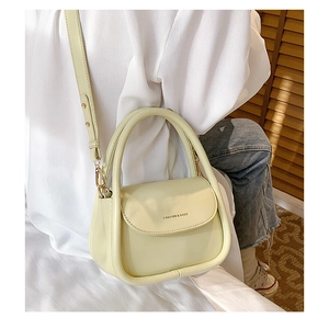 Detail of cream yellow mini flap bag with cylindrical handle and long shoulder strap