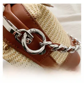 Detailed close-up of straw woven bag with brown leather trim and silver metal hardware