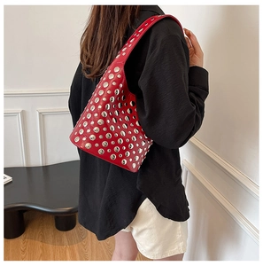 Detail of red glossy leather bucket bag with silver metal rivets and embroidery threads