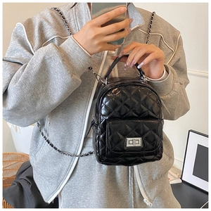 Detailed view of black quilted mini backpack with silver metal twist-lock and chain strap