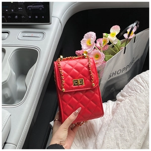 Close-up of a red quilted chain bag with a gold twist lock inside a luxury car