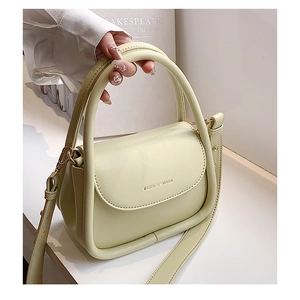Detail of light green fashion bag showing leather texture and debossed logo