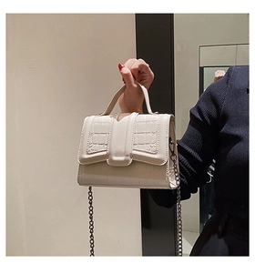Dettaglio della borsa beige in similpelle a coccodrillo con tracolla a catena d'oro