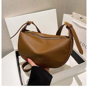 Detailed macro of brown crescent shoulder bag with lychee grain texture and gold hardware
