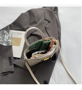 Detail view of beige croc-embossed handbag showing space for phones and lipstick