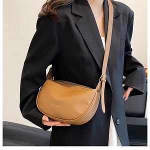 Detailed view of a brown pebbled leather half-moon crossbody bag with gold hardware