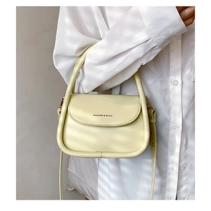 Chic cream yellow crossbody bag styled with a white shirt in a modern fashion setup