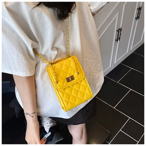 Detail view of yellow quilted crossbody bag with gold chain strap on a female model