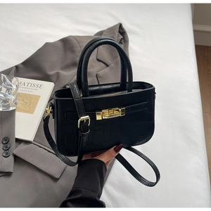 Detail of black crocodile-embossed PU handbag with gold hardware clasp and sleek handles