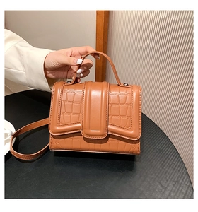 Dettaglio della borsa in pelle marrone caramello a motivo coccodrillo con manico elegante