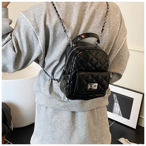 Rear view of a model wearing a black quilted mini backpack with silver chain straps