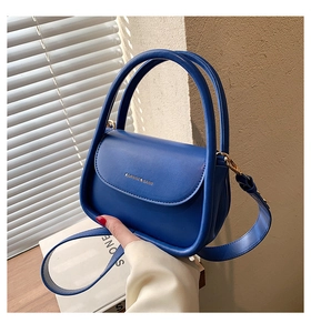Detail of royal blue leather handbag with gold lettering and top handle design