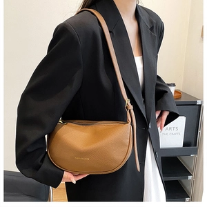 Detail of brown crescent bag featuring pebbled leather texture and adjustable strap