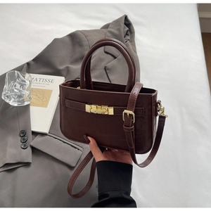 Detailed view of dark brown faux leather bag featuring crocodile pattern and gold twist lock